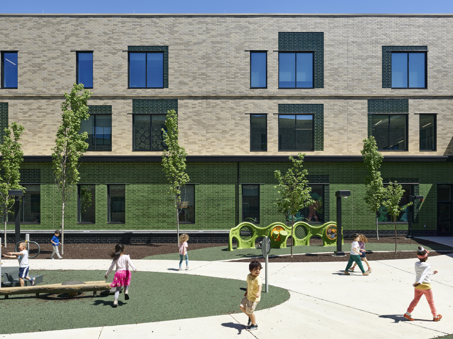 Rendering of an outdoor playground in front of a multistory school filled with green spaces, trees, and play equipment