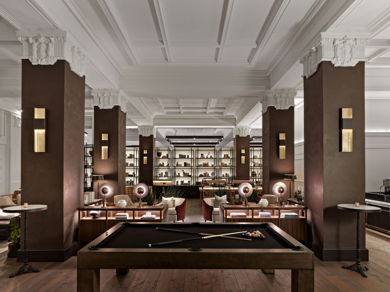 The Surety Hotel with billiard tables and wood pillars and white Corinthian capitals in room with recessed ceiling details