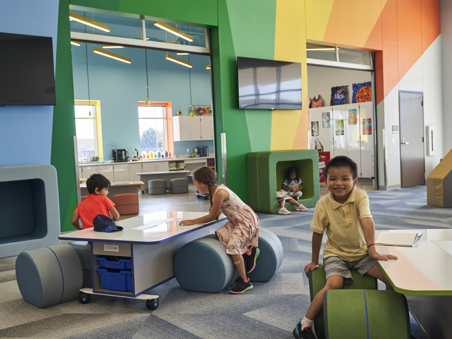 A colorful, modern classroom with children engaging with interactive furniture and books.