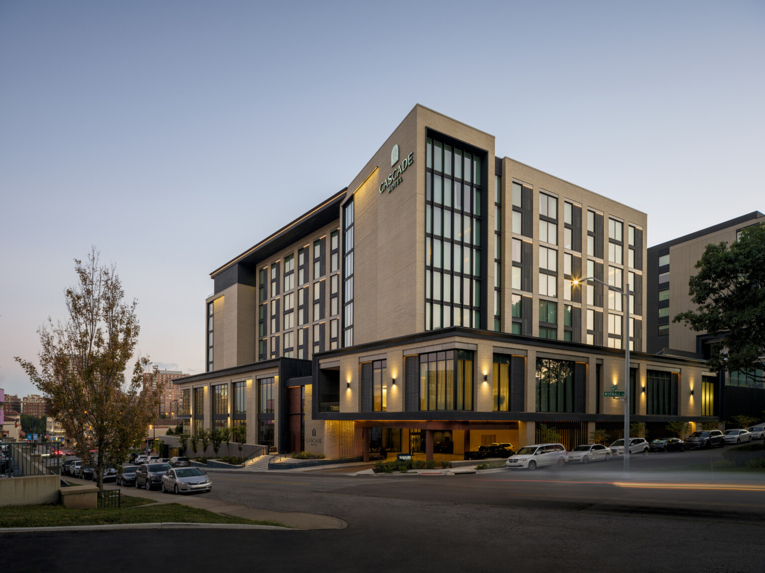 Hotel exterior at dusk, mid-rise modern building with warm tones