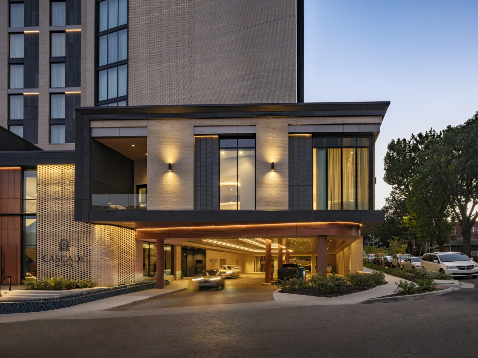 Modern hotel porte cochere dimly lit. Large windows filled with light.