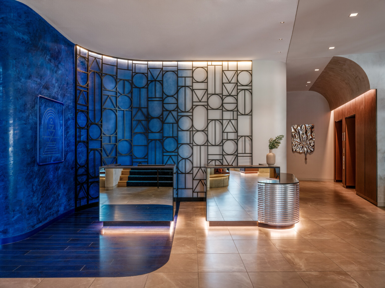 hotel lobby and front desk at the Cascade Hotel, a Tribute Portfolio by Marriott, large metal art piece curves on blue wall, unique and curved shapes create a memorable experience