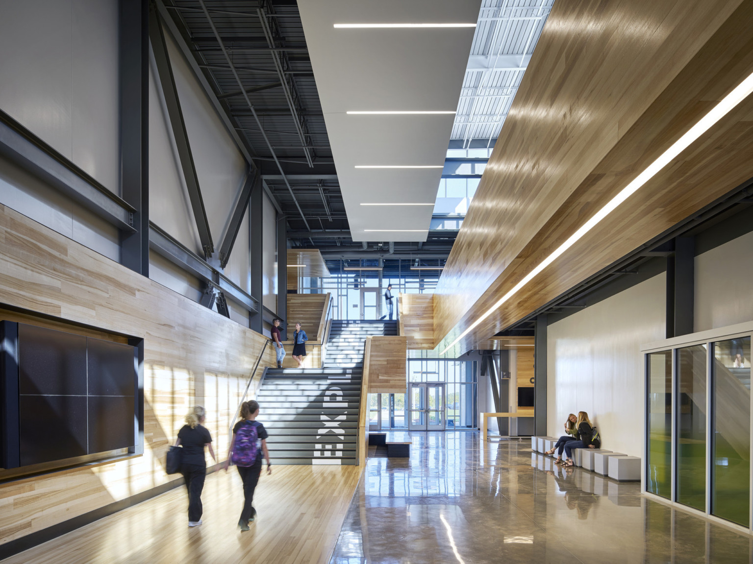 Missouri Innovation Campus interior hallway facing double height glass windows at entry and black staircase with wood walls