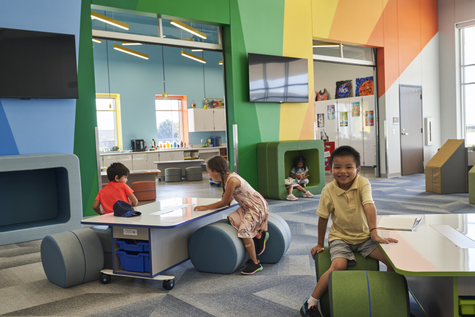 A colorful, modern classroom with children engaging with interactive furniture and books.