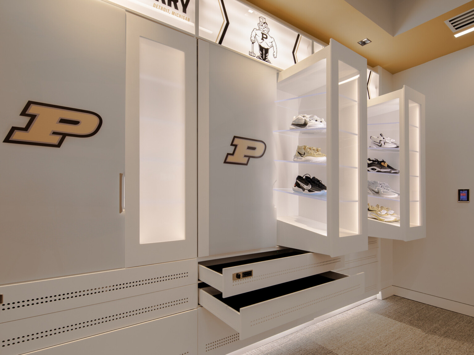 White cabinets and shelves built into a wall with shoe displays and drawers opened with Purdue logo prominently displayed