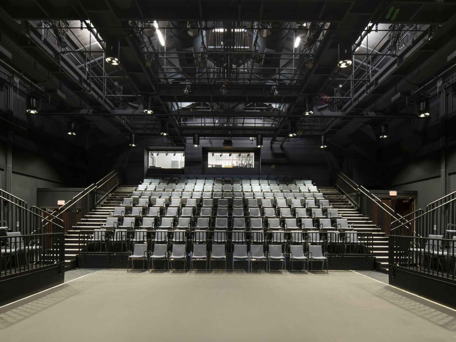 Blackbox theatre with rows of chairs to the front and sides with large windows above