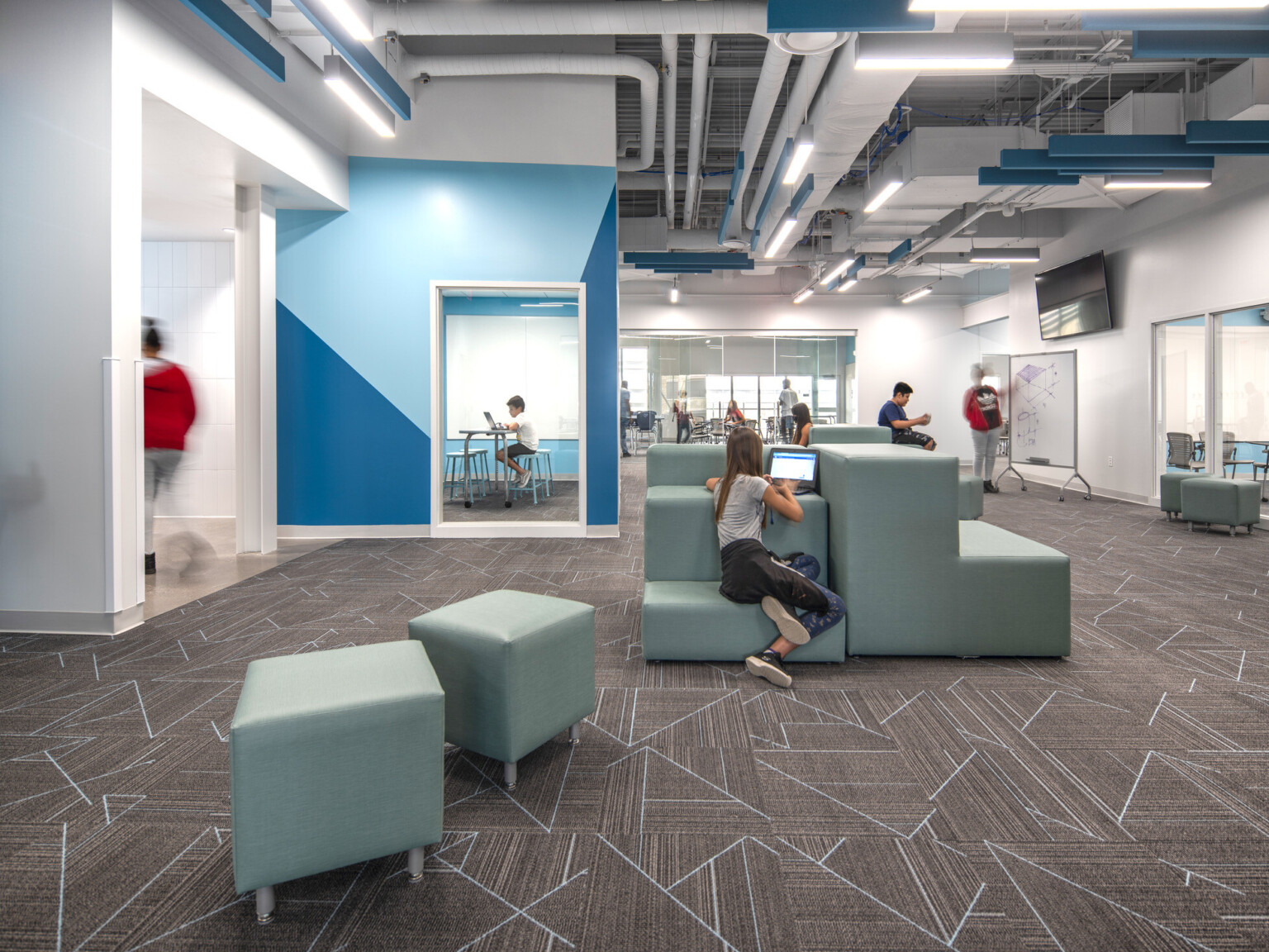 Moveable, modular furniture fills the space of a middle school with a study room in the background, white boards line the walls