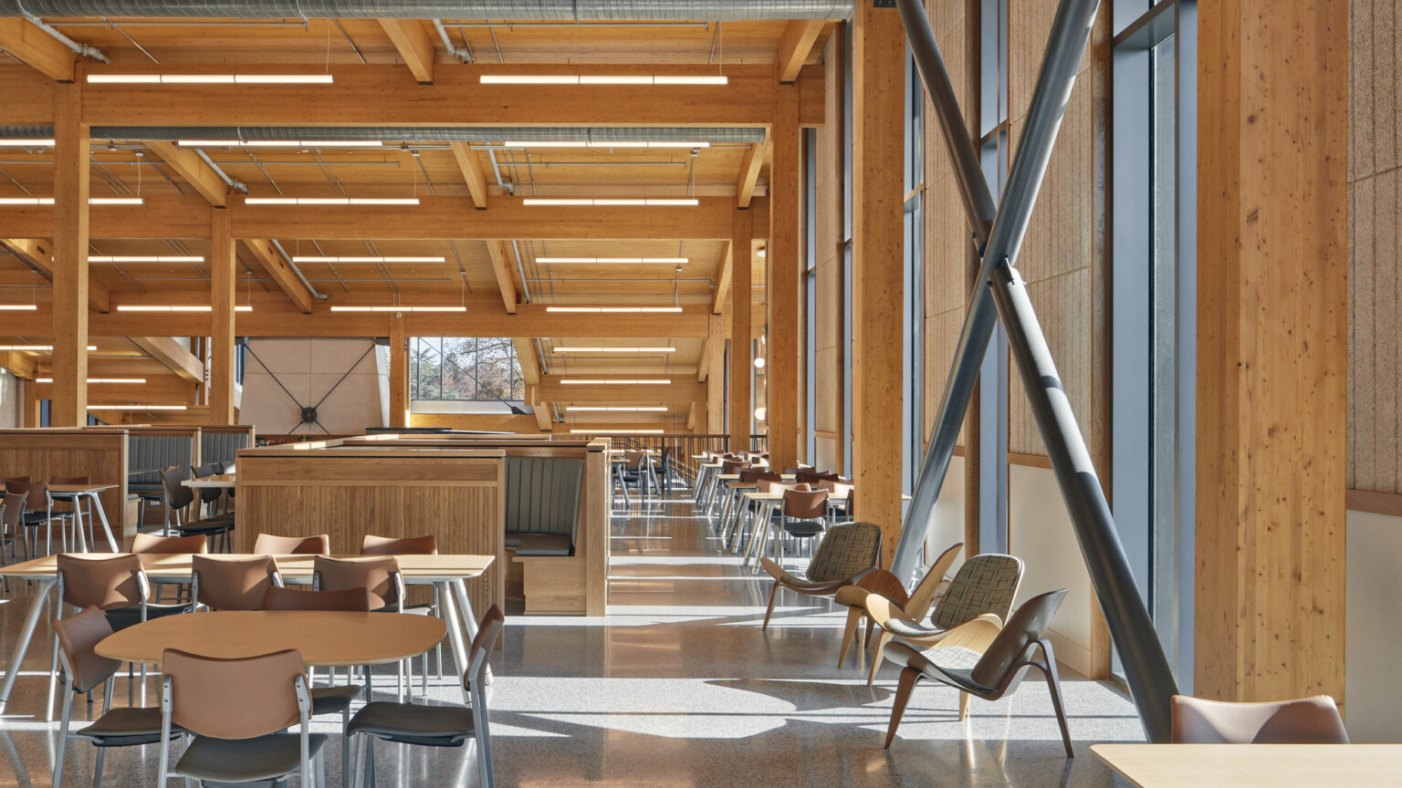 mass timber triple-height ceilings and stone walls, overhead energy-efficient low-wattage lighting, exposed ducting, steel supports, floor-to-ceiling windows provide natural light, wood and steel seating