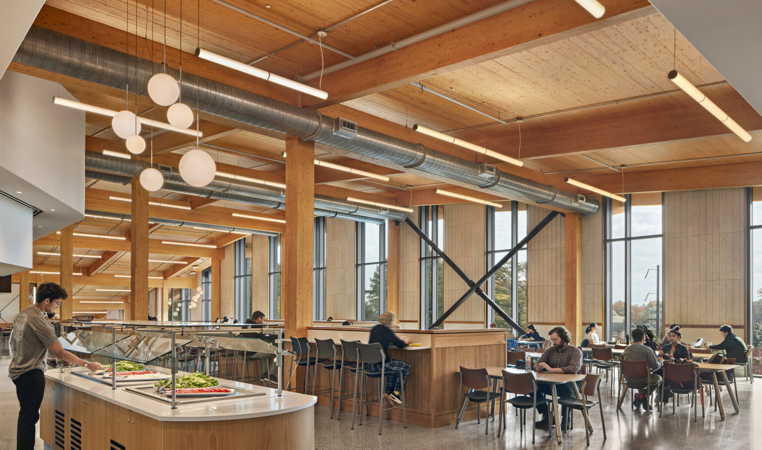 Dining area with flexible seating below wood ceiling with beam details, hanging rod lights, fireplace with white chimney back