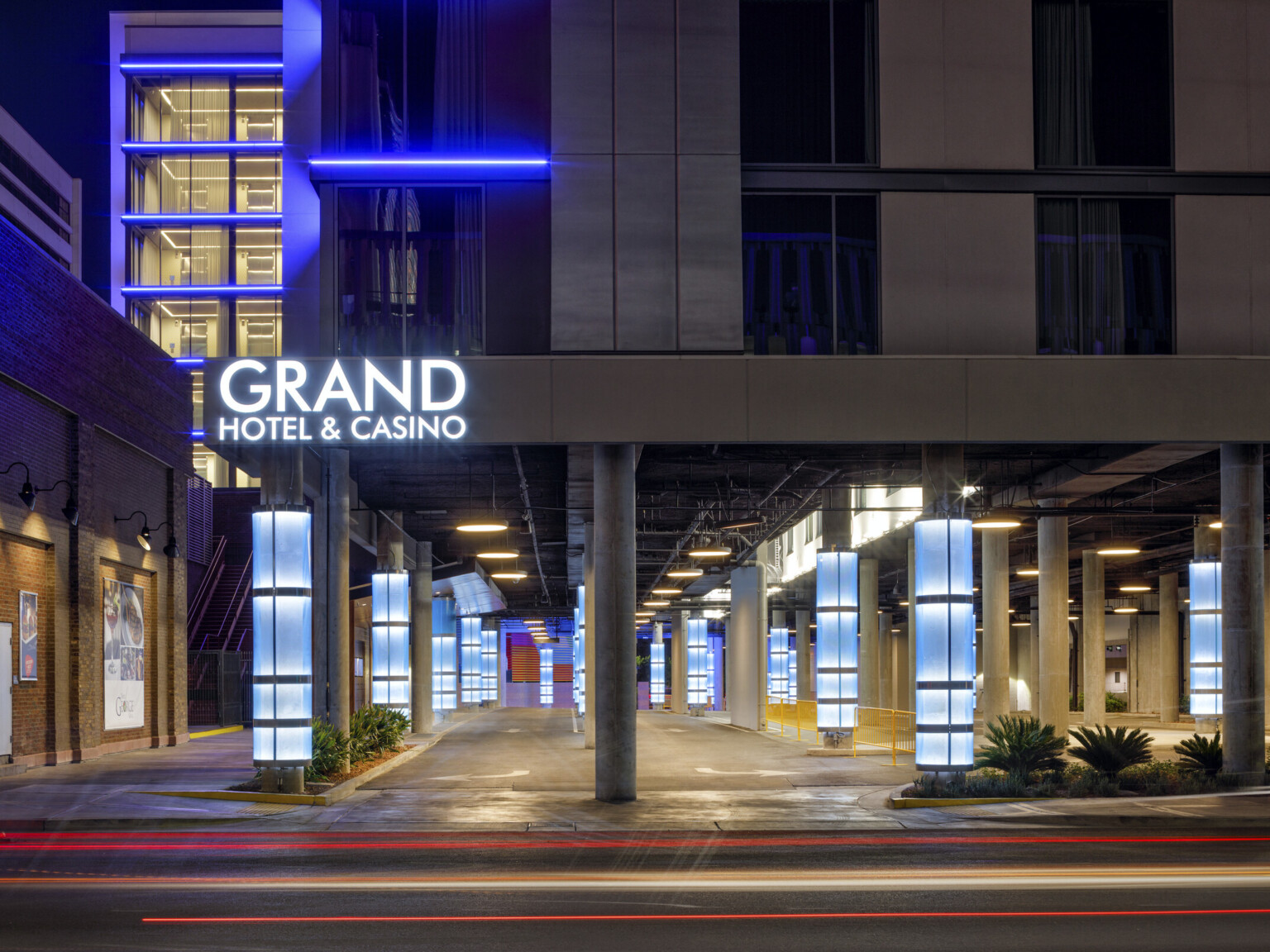 Large building sitting on concrete beams with blue accent lighting highlighting windows with Grand Hotel and Casino words in white light