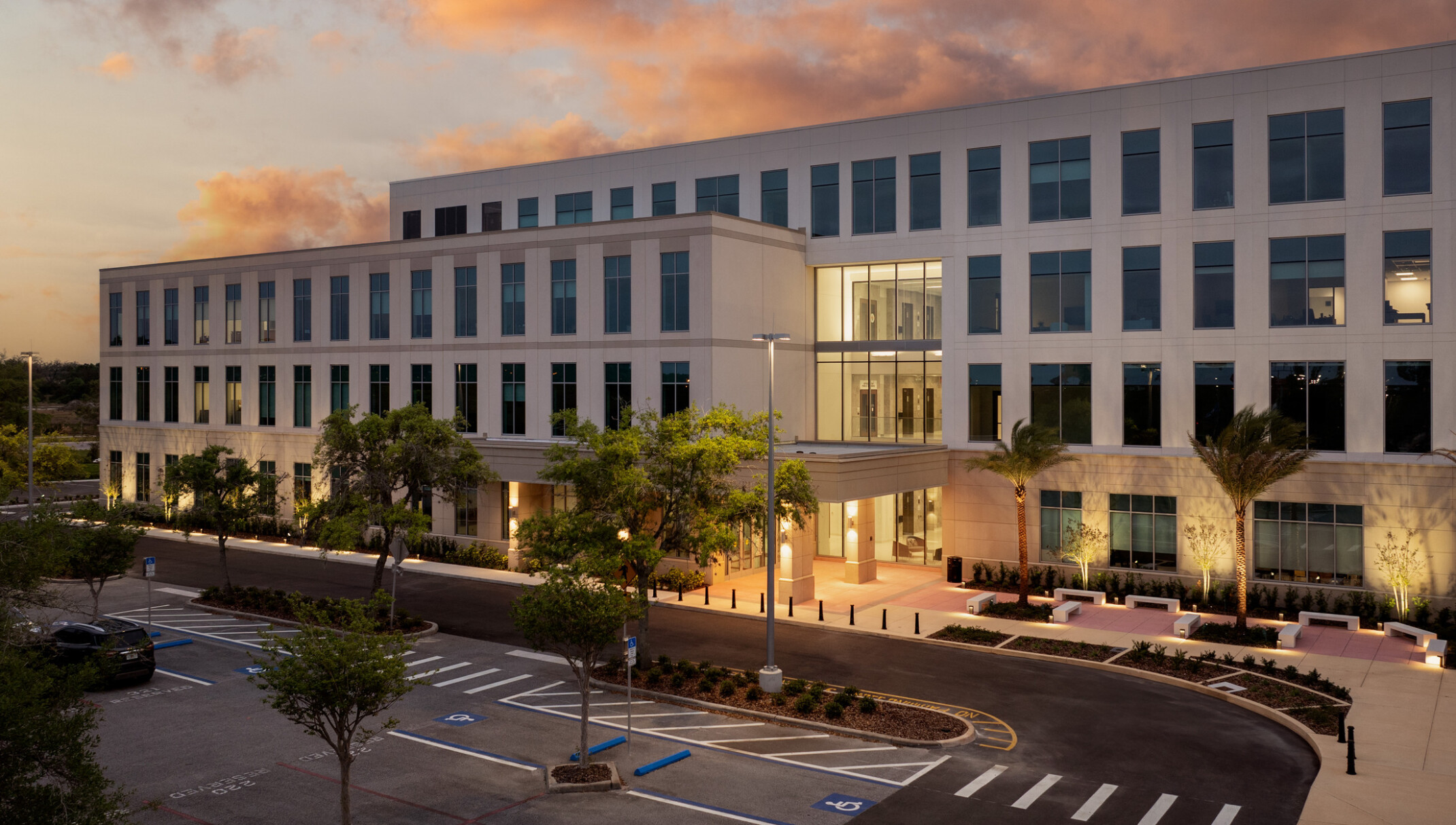 Multistory white building filled with dark windows with a bight lit entryway