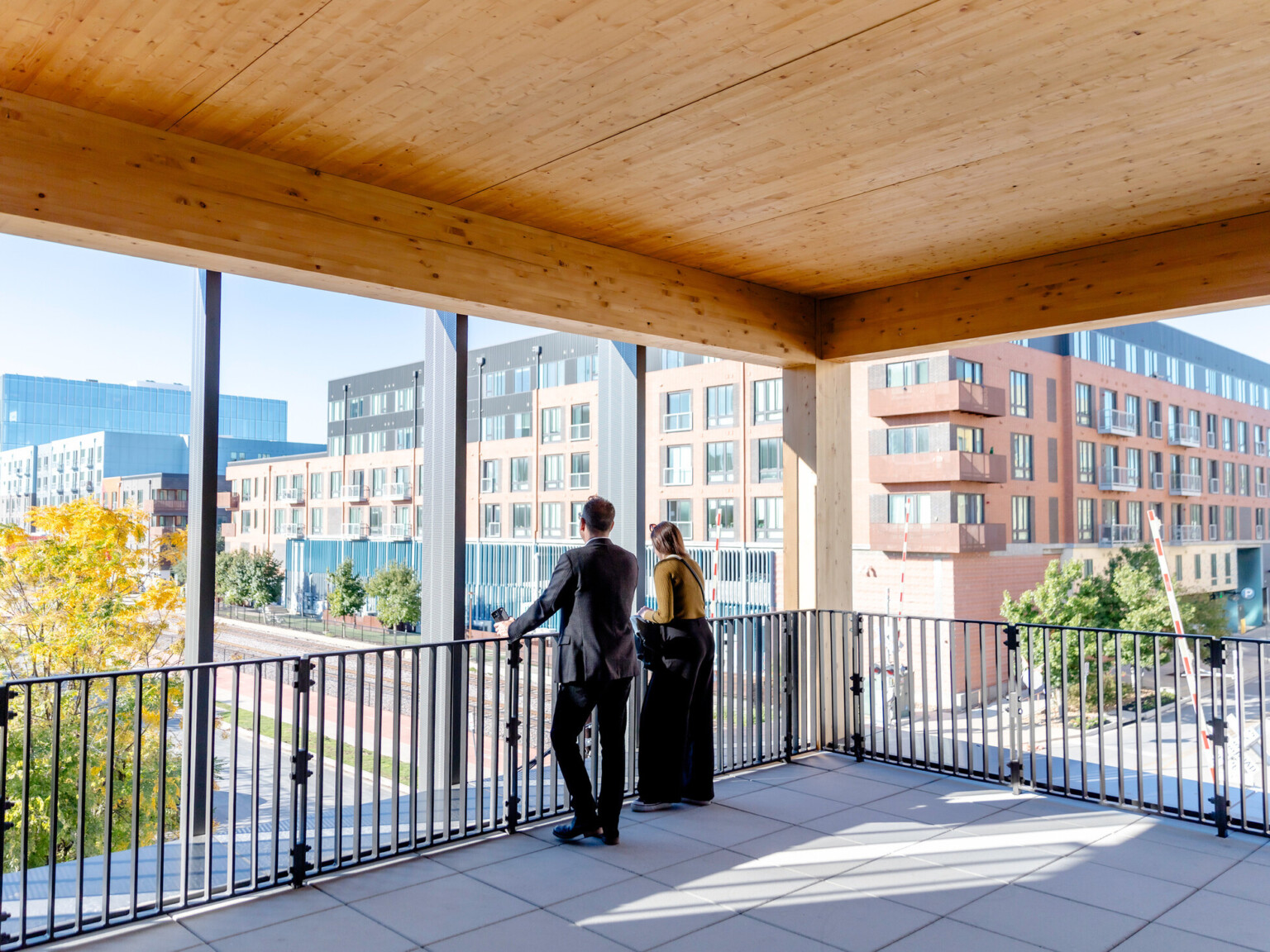 Two people standing at a black railing looking out floor to ceiling windows