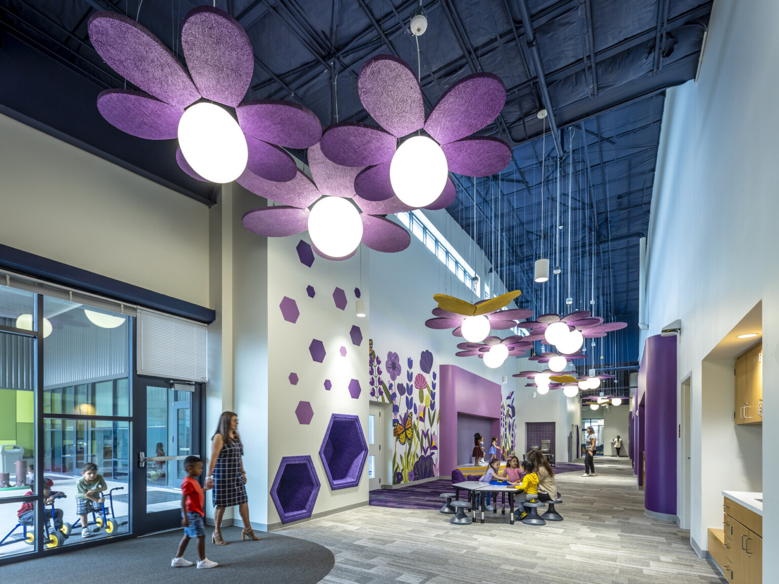 Entry to the Tomball Early Excellence Academy with grey walls, purple accents, and purple flower lighting suspended from the ceiling.