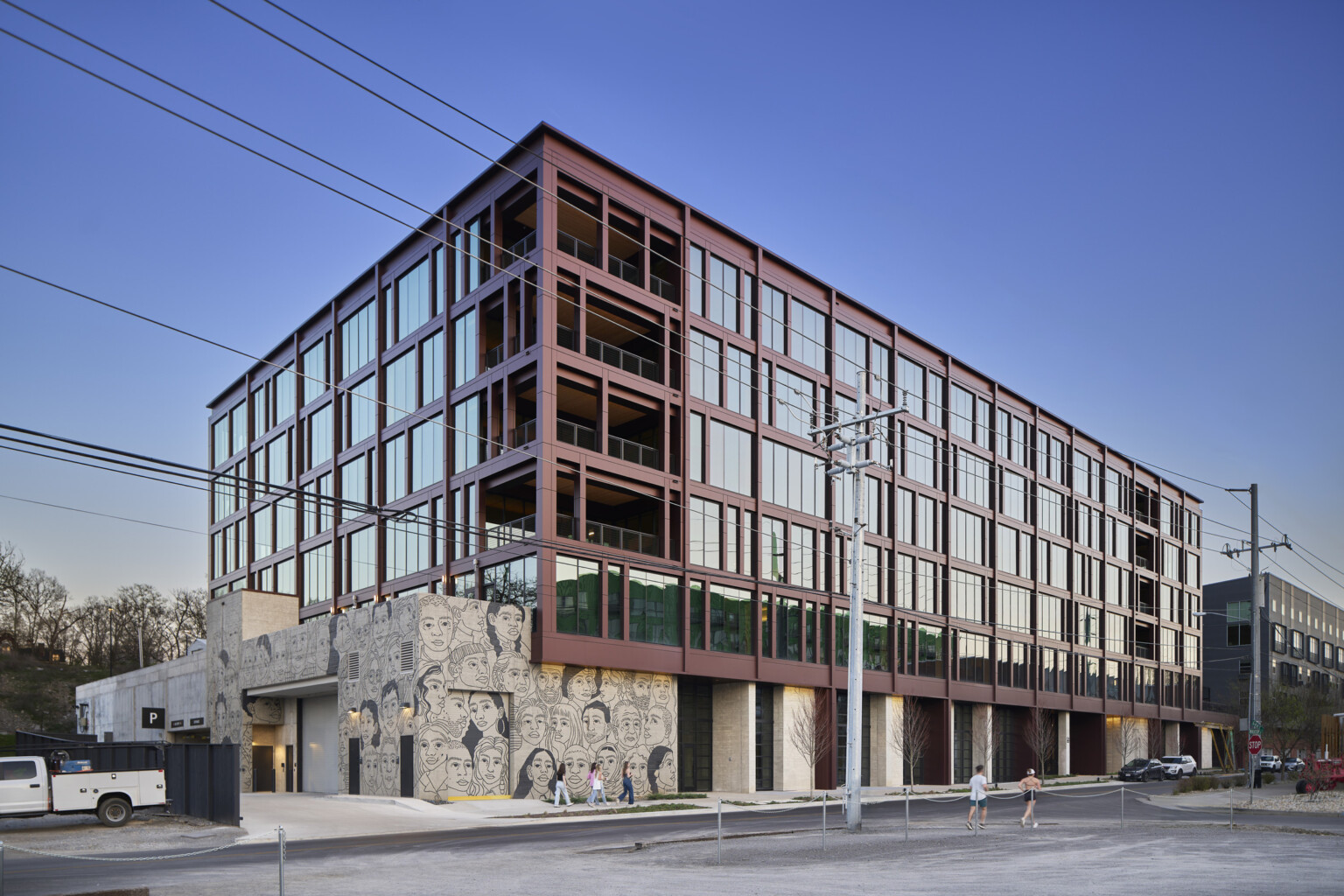 Multistory mass timber building with rows of windows of floor to ceiling windows and large common area balconies on each floor