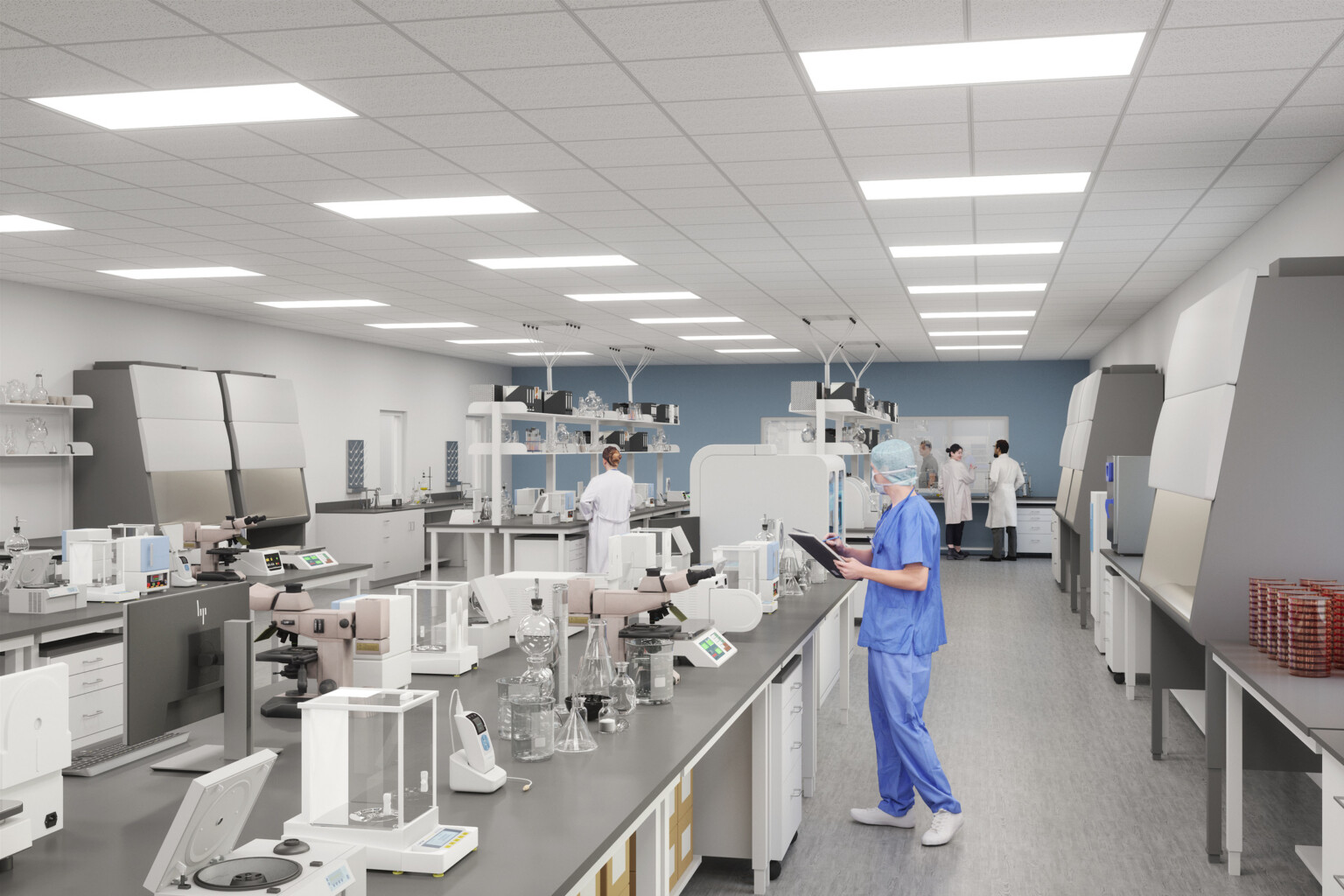 Person in blue scrubs working in a lab with equipment on grey tabletops