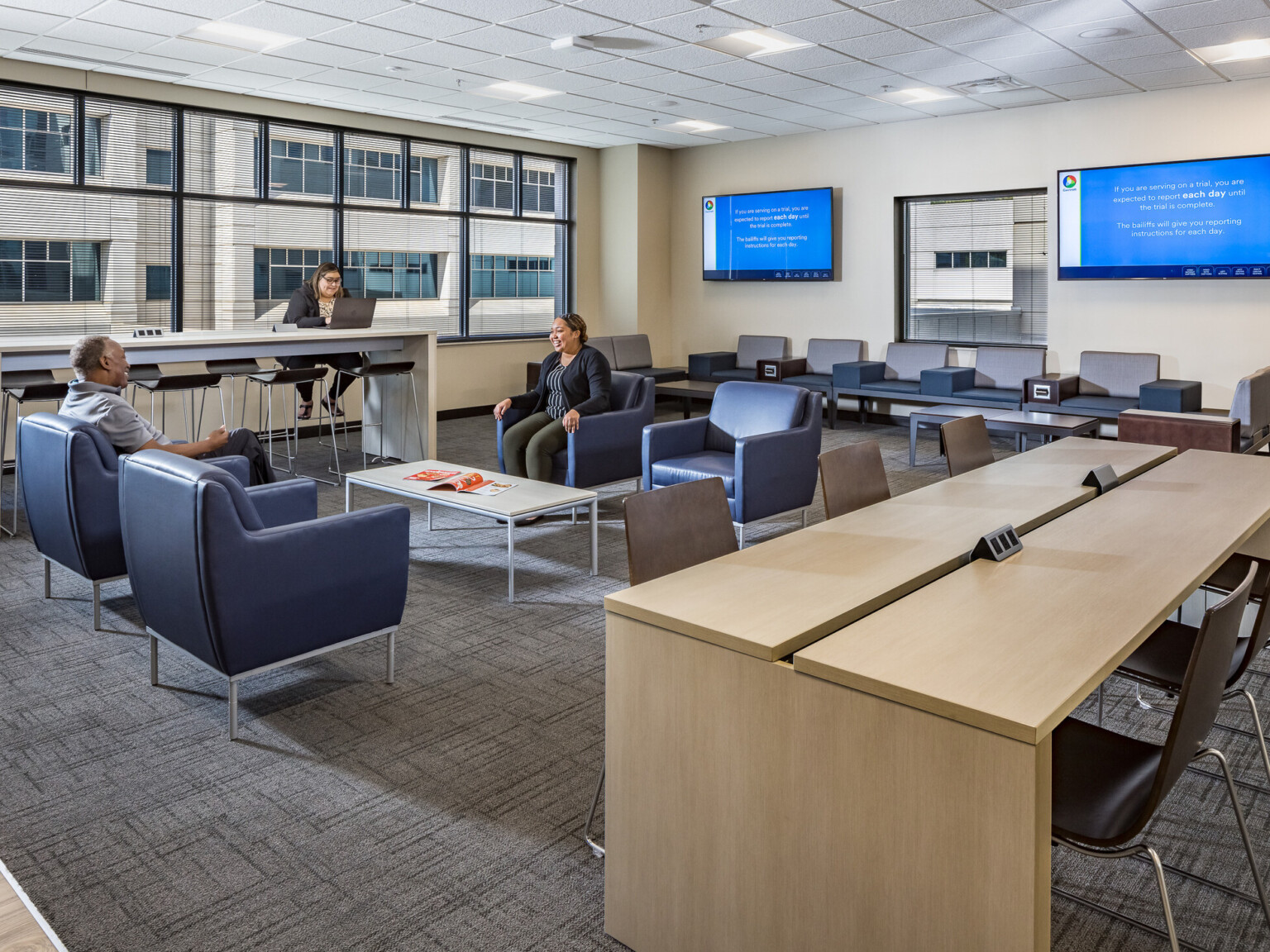 Office waiting room filled with tables and chairs with a wall of windows