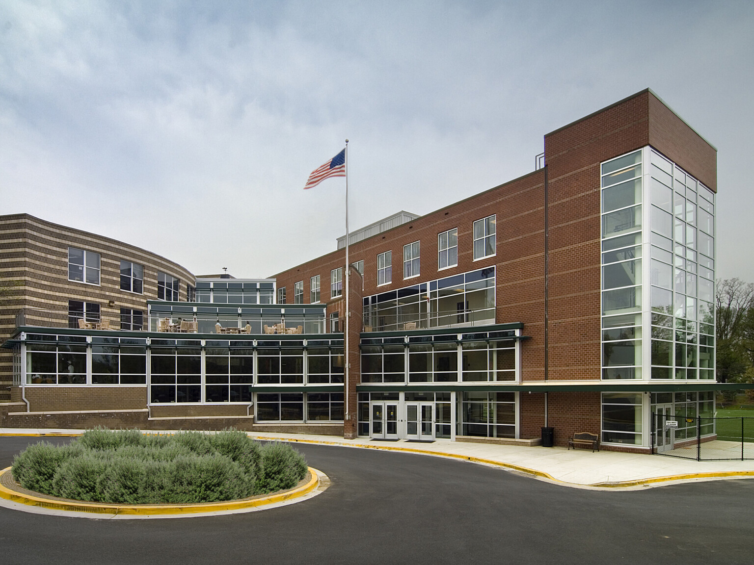 Exterior of Georgetown Day School Athletic Center showing a multistory building filled with windows with the American flag on a flagpole out front