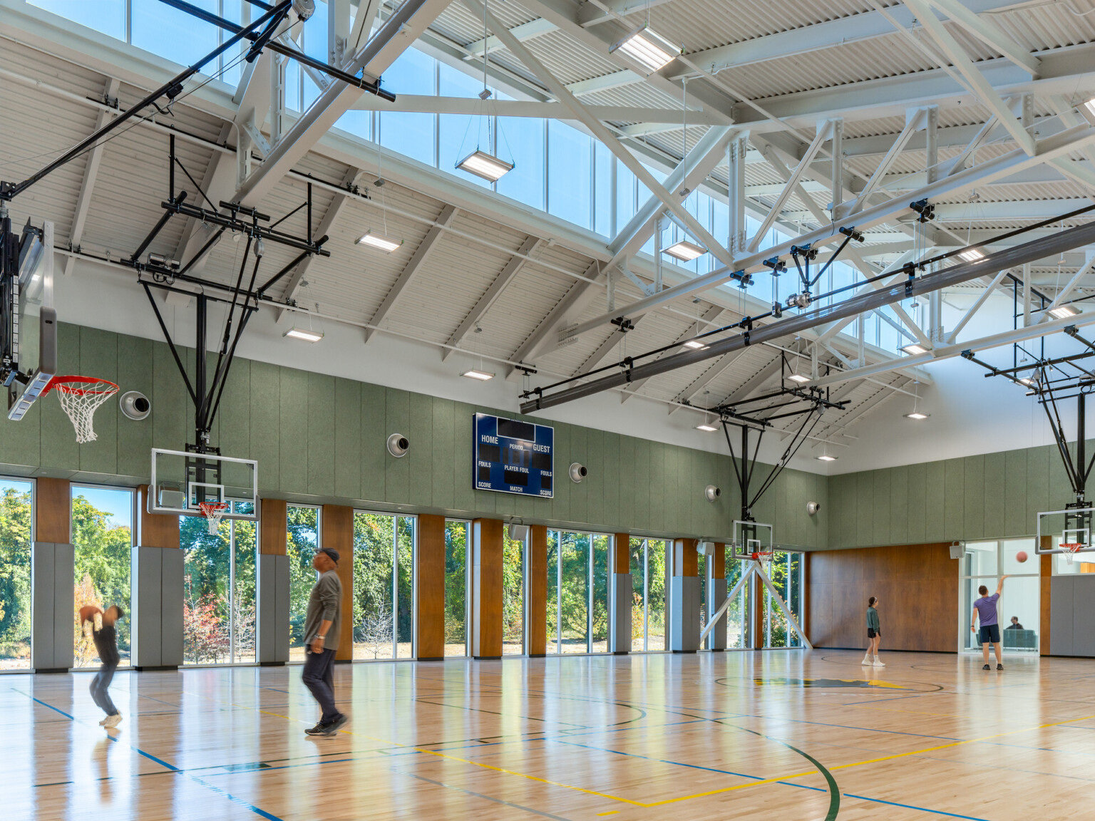 Indoor basketball court with hoops suspended from the ceiling filled with people playing basketball.