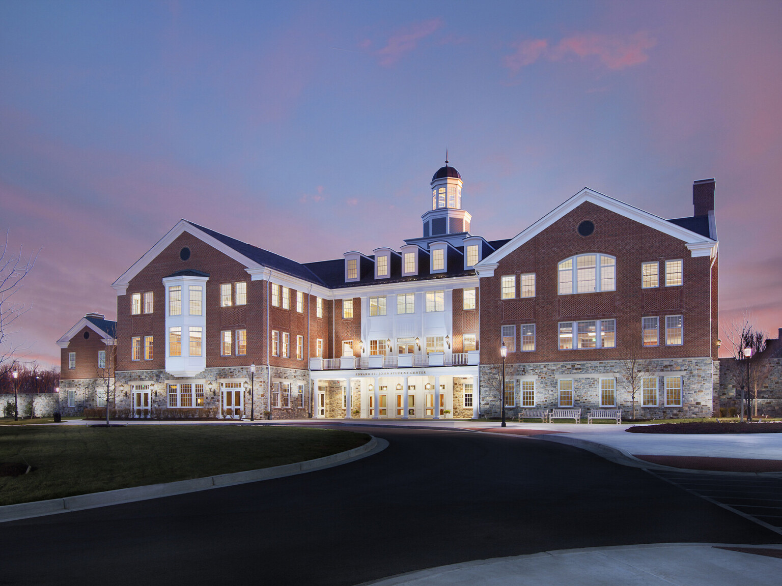 Exterior image of the Edward St. John Student Center at McDonogh School showing a brick and stone exterior with white accents and railings