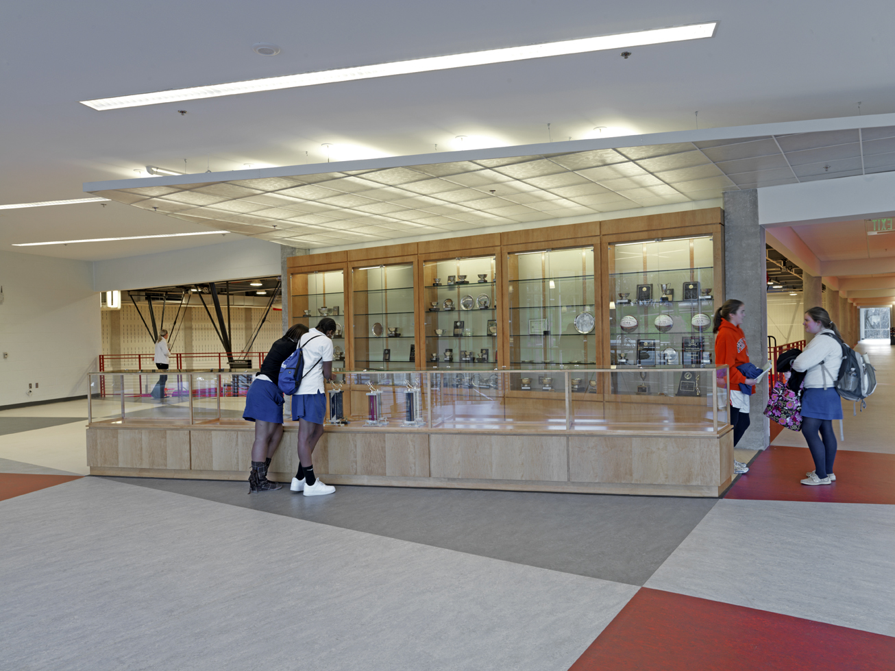 People standing together in lobby, socializing and waiting with trophy cases in the background