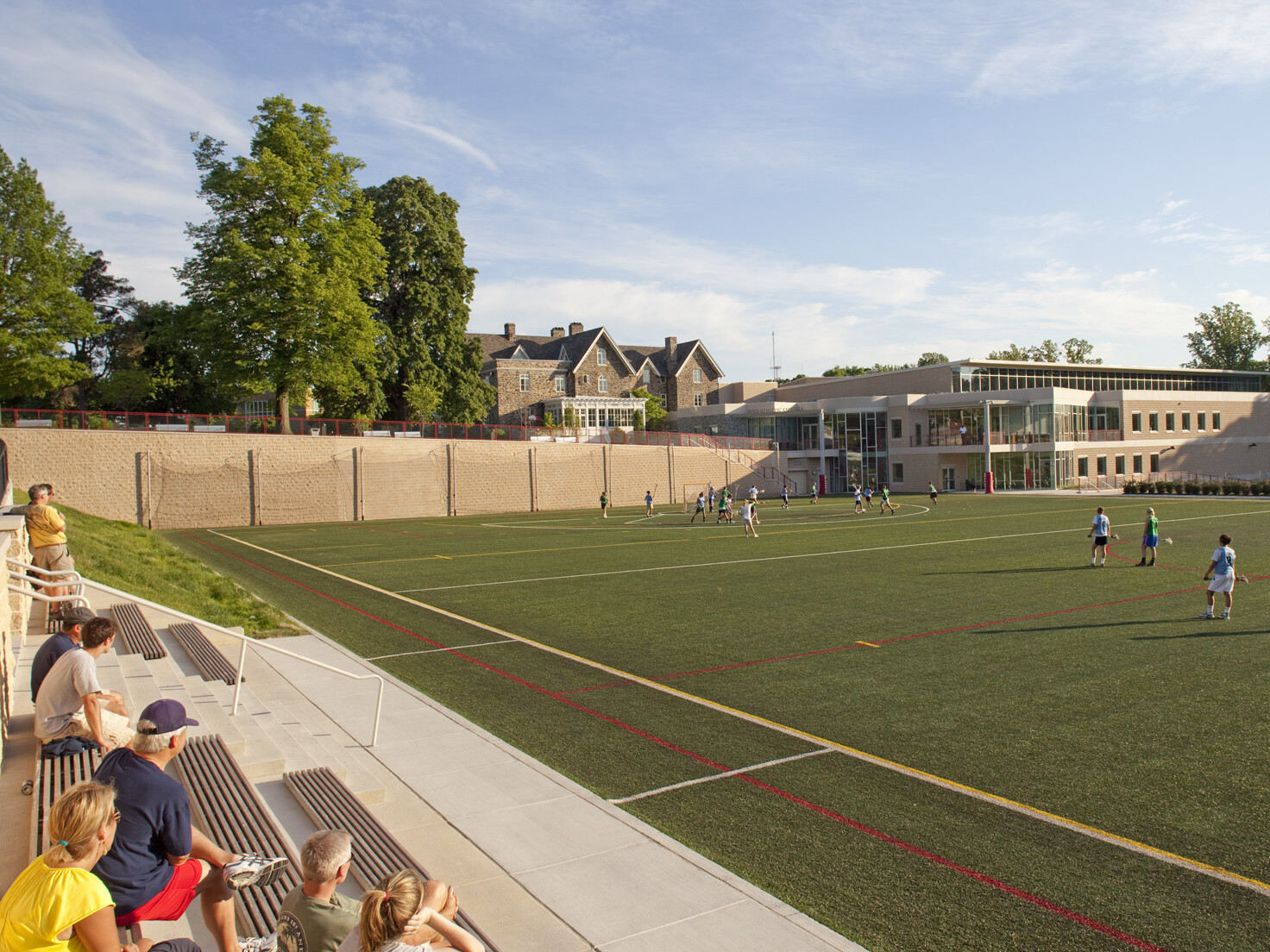 A soccer field with green grass, white boundary lines, and two goals at opposite ends in front of a brick building