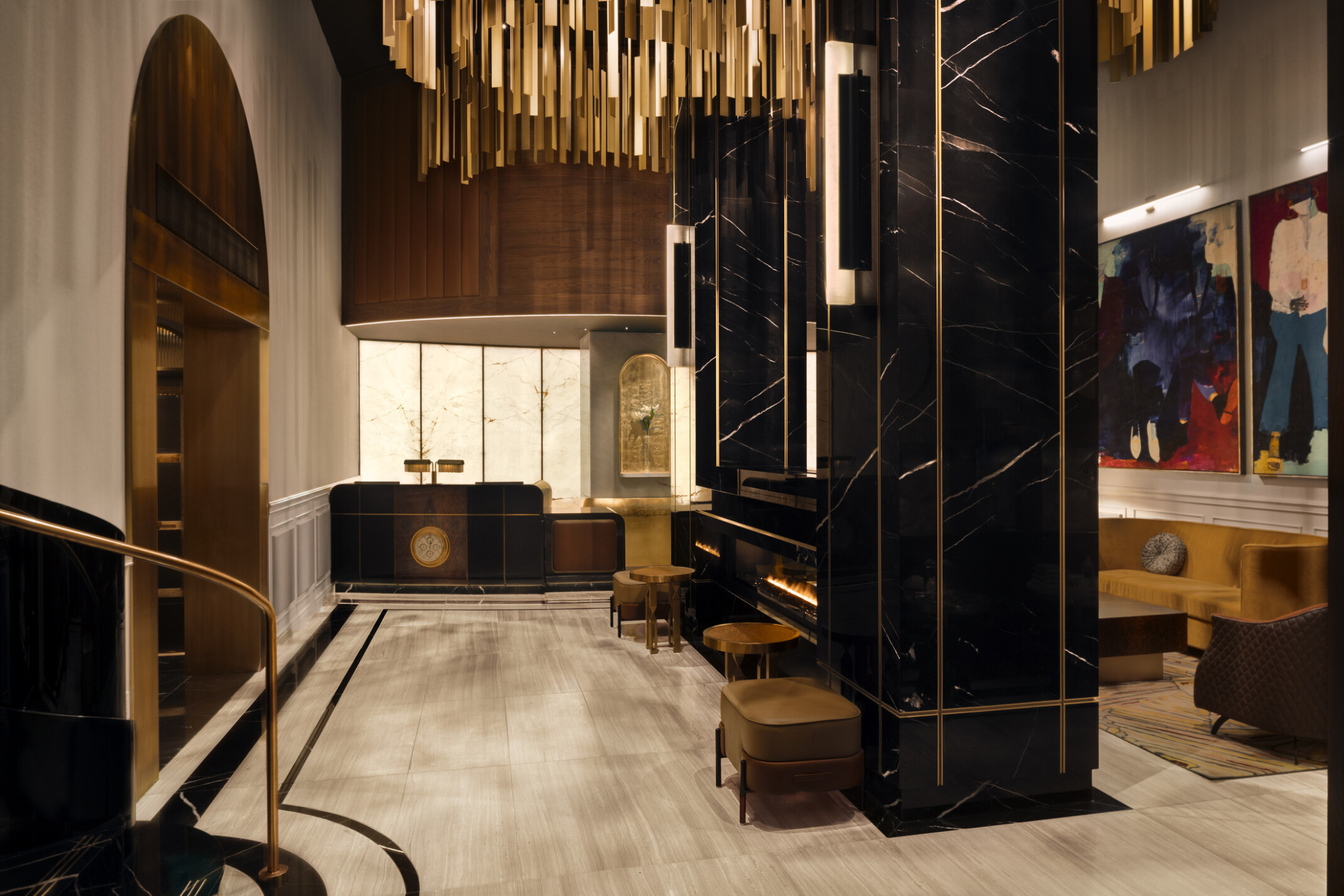 Glamorous hotel lobby showing black marble fireplace with modern furnishings and gold accents suspended from the ceiling