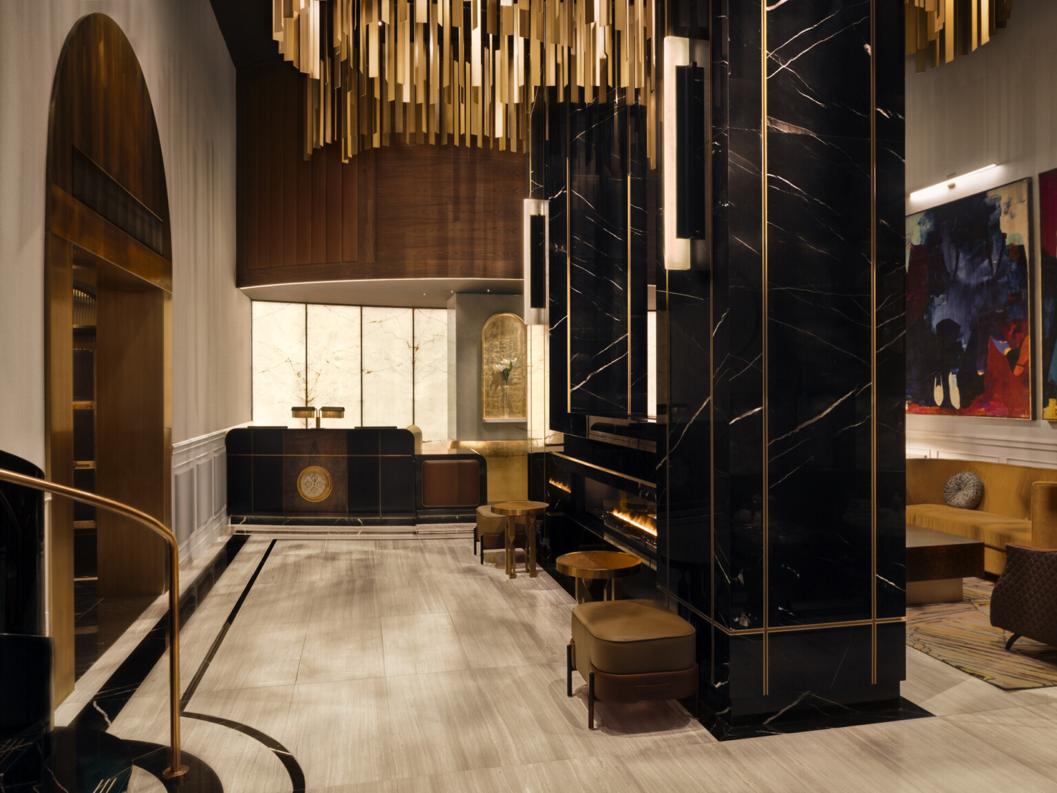 Glamorous hotel lobby showing black marble fireplace with modern furnishings and gold accents suspended from the ceiling