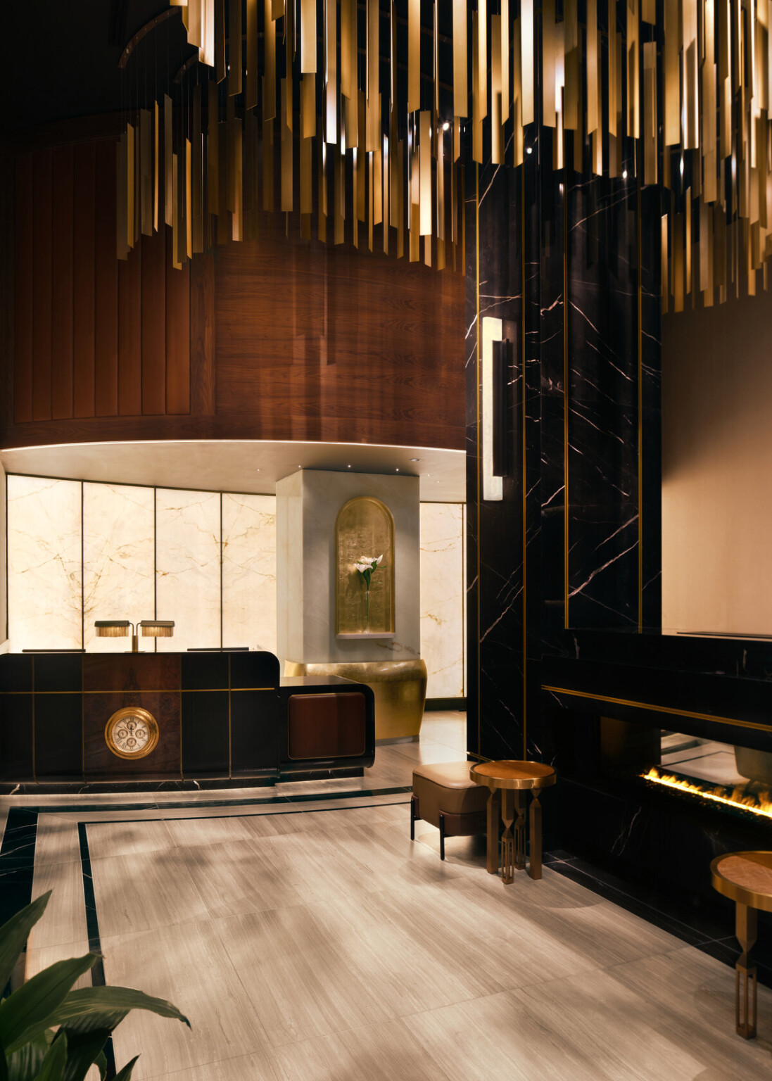 Glamorous hotel lobby showing black marble fireplace with modern furnishings and gold accents suspended from the ceiling