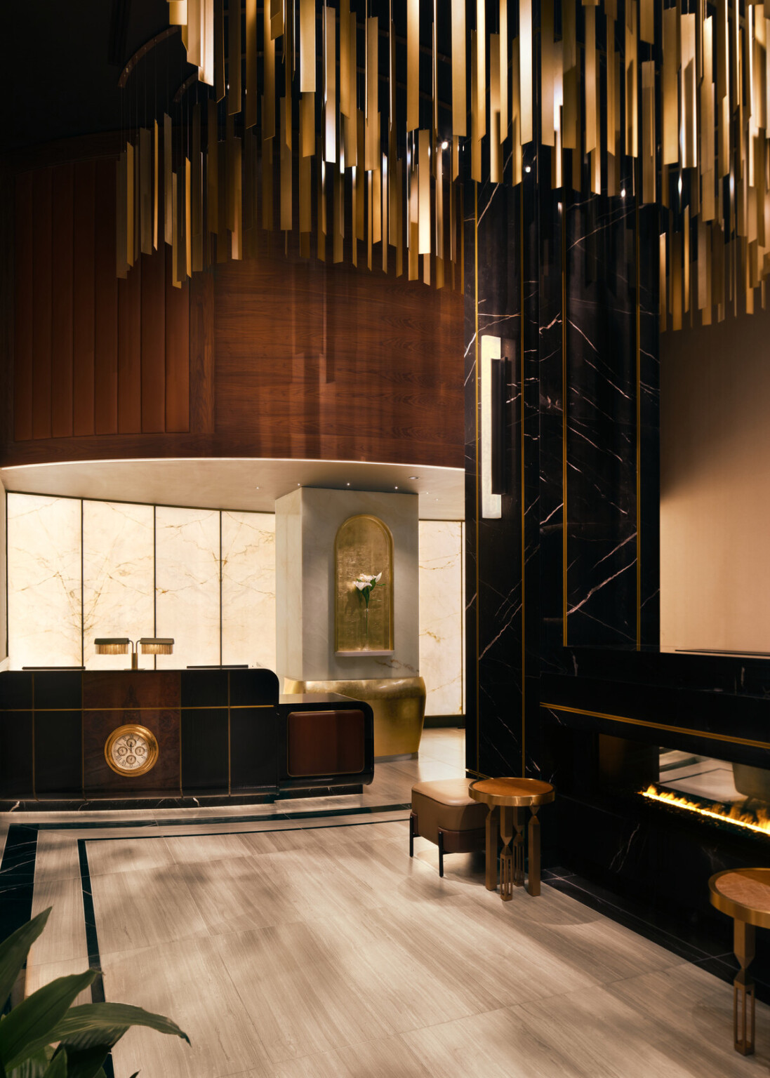 Glamorous hotel lobby showing black marble fireplace with modern furnishings and gold accents suspended from the ceiling