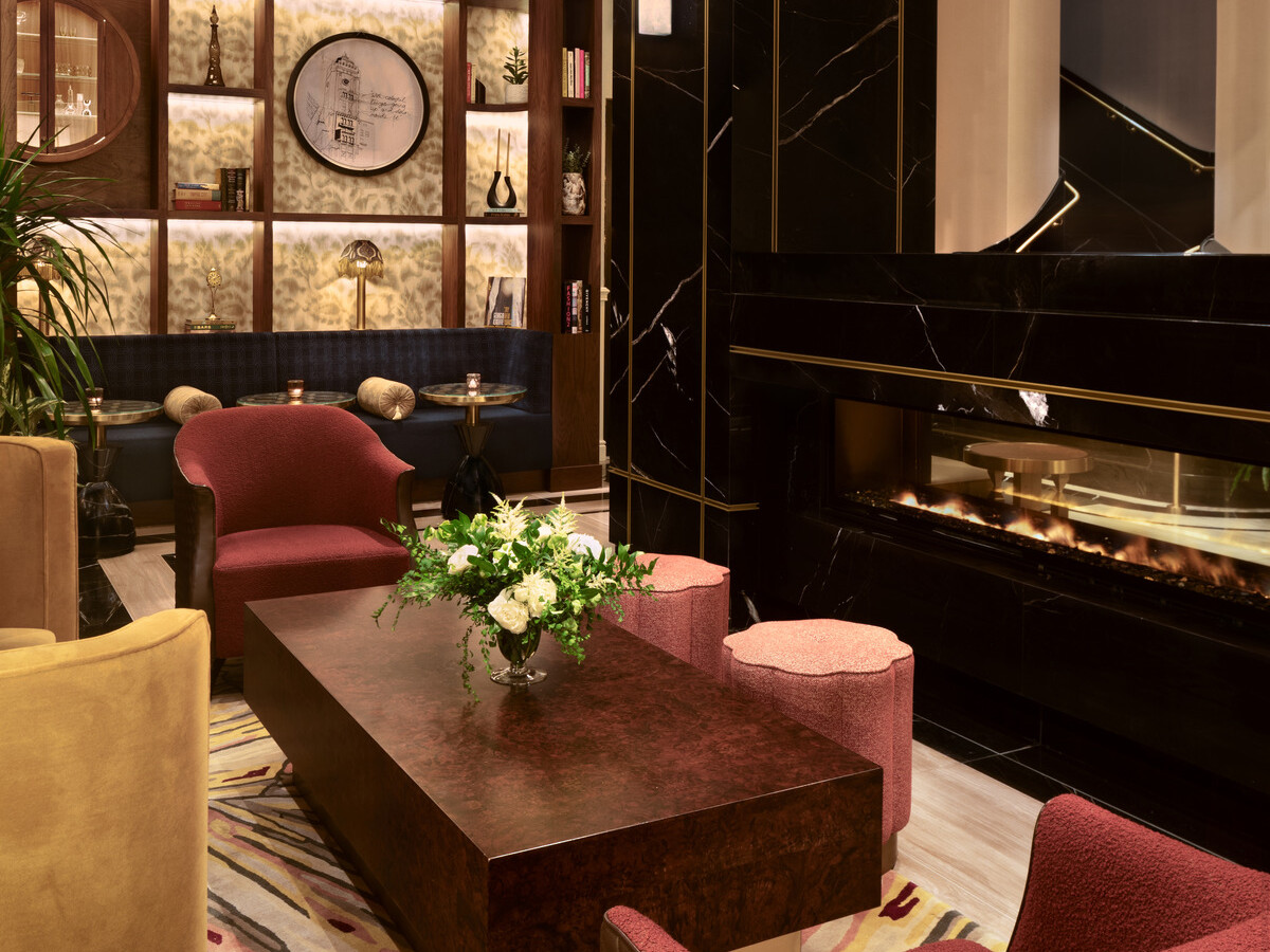 Glamorous hotel lobby showing black marble wall accents, modern furnishings, gold accents suspended from the ceiling, and a wooden display on the back wall