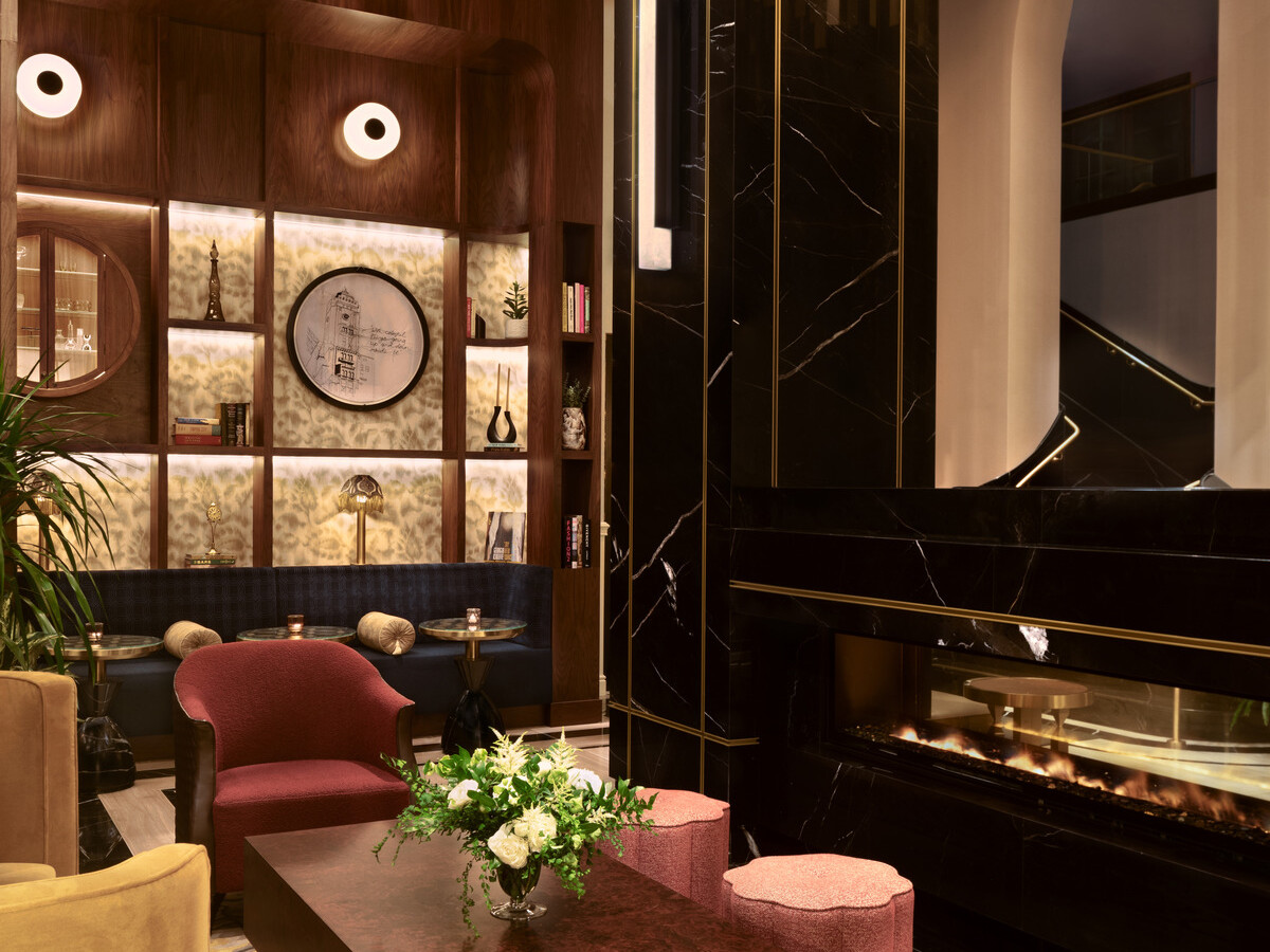 Glamorous hotel lobby showing black marble wall accents, modern furnishings, gold accents suspended from the ceiling, and a wooden display on the back wall