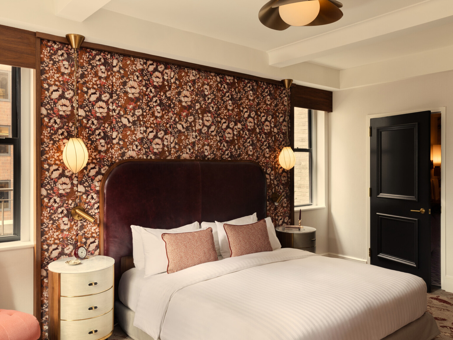 Glamorous hotel room showing wooden doors, orange accent chair, and white bedding