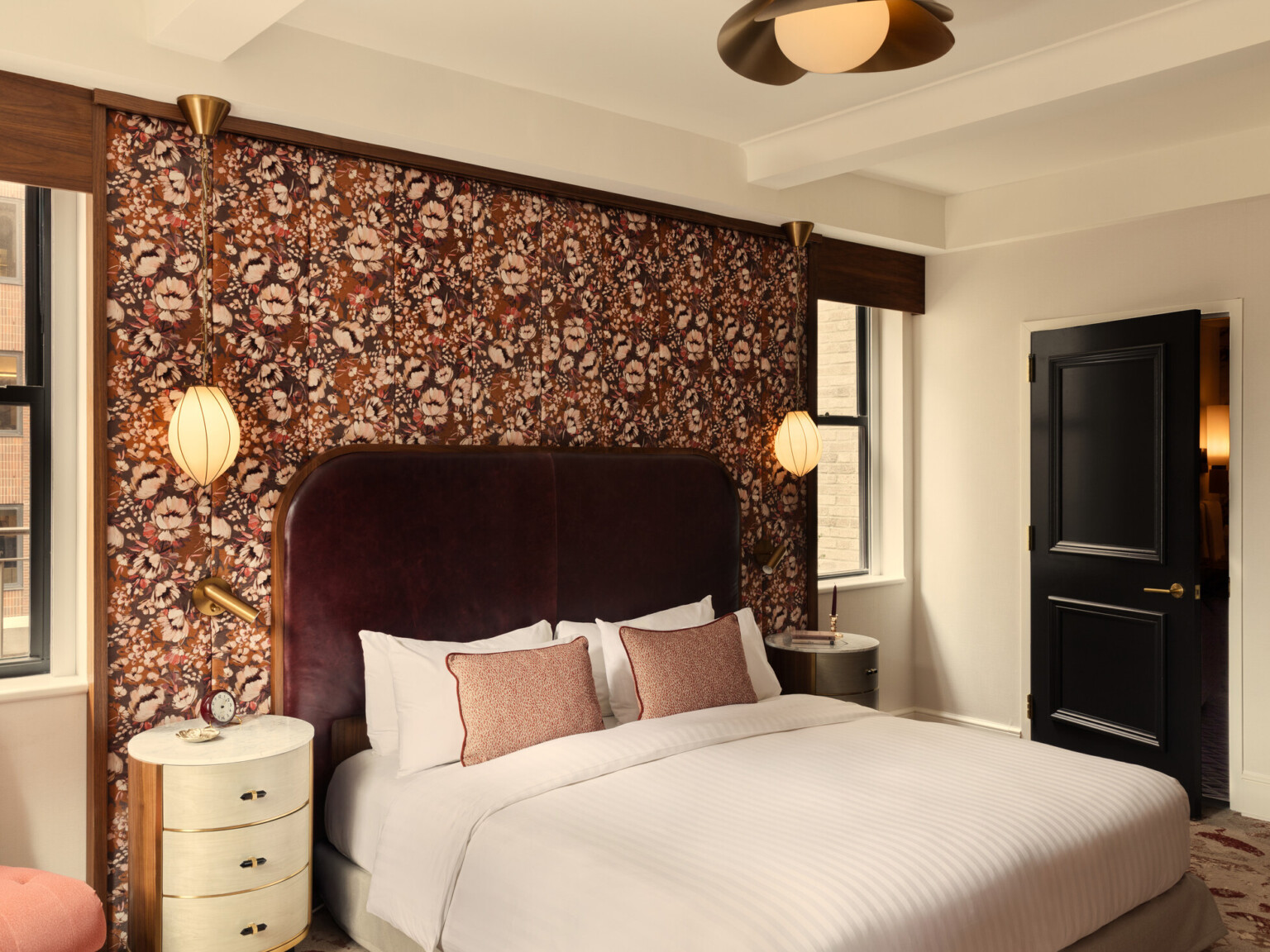 Glamorous hotel room showing wooden doors, orange accent chair, and white bedding