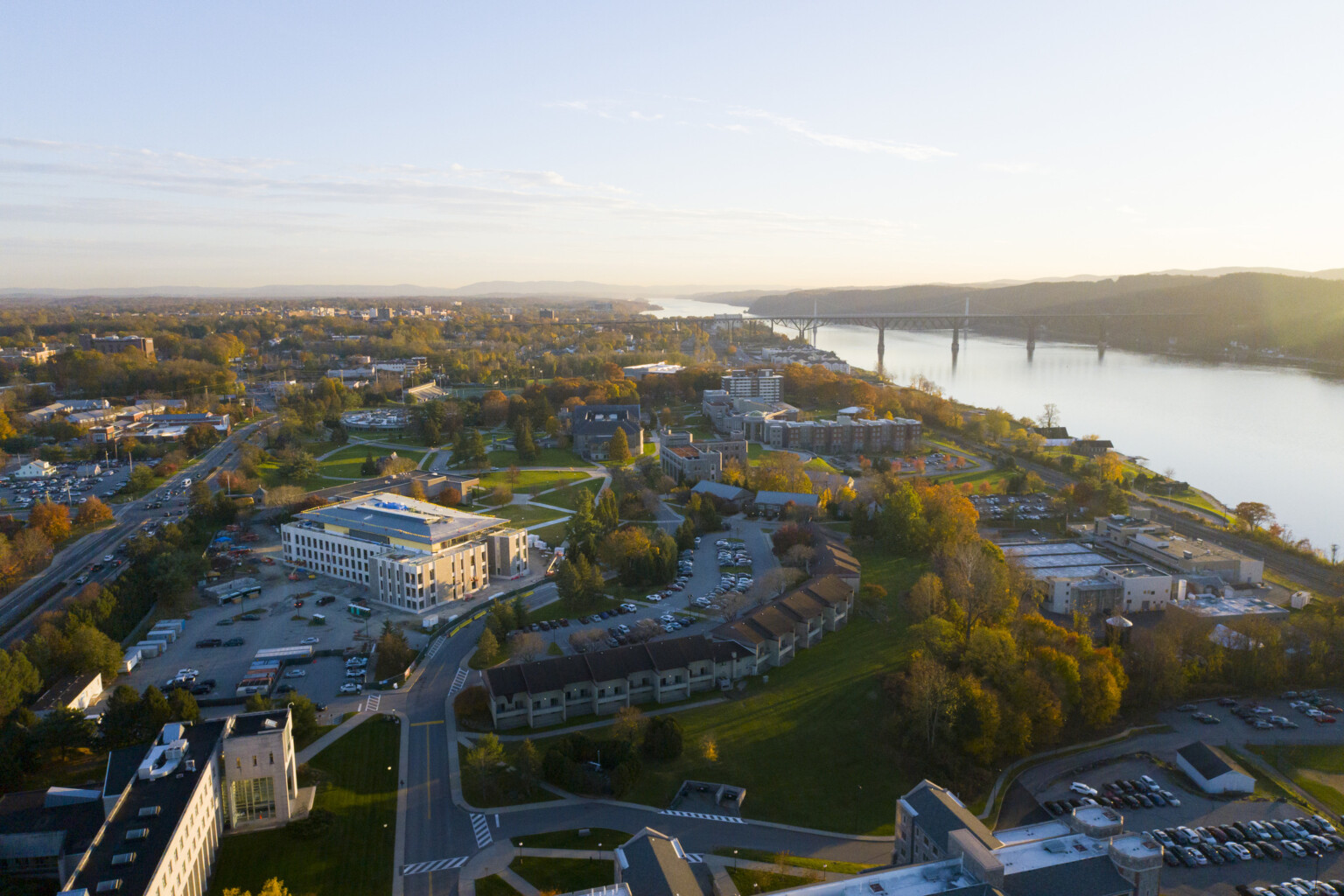 Aerial view of Marist College showing buildings settled in fall colored foliage in front of a river.