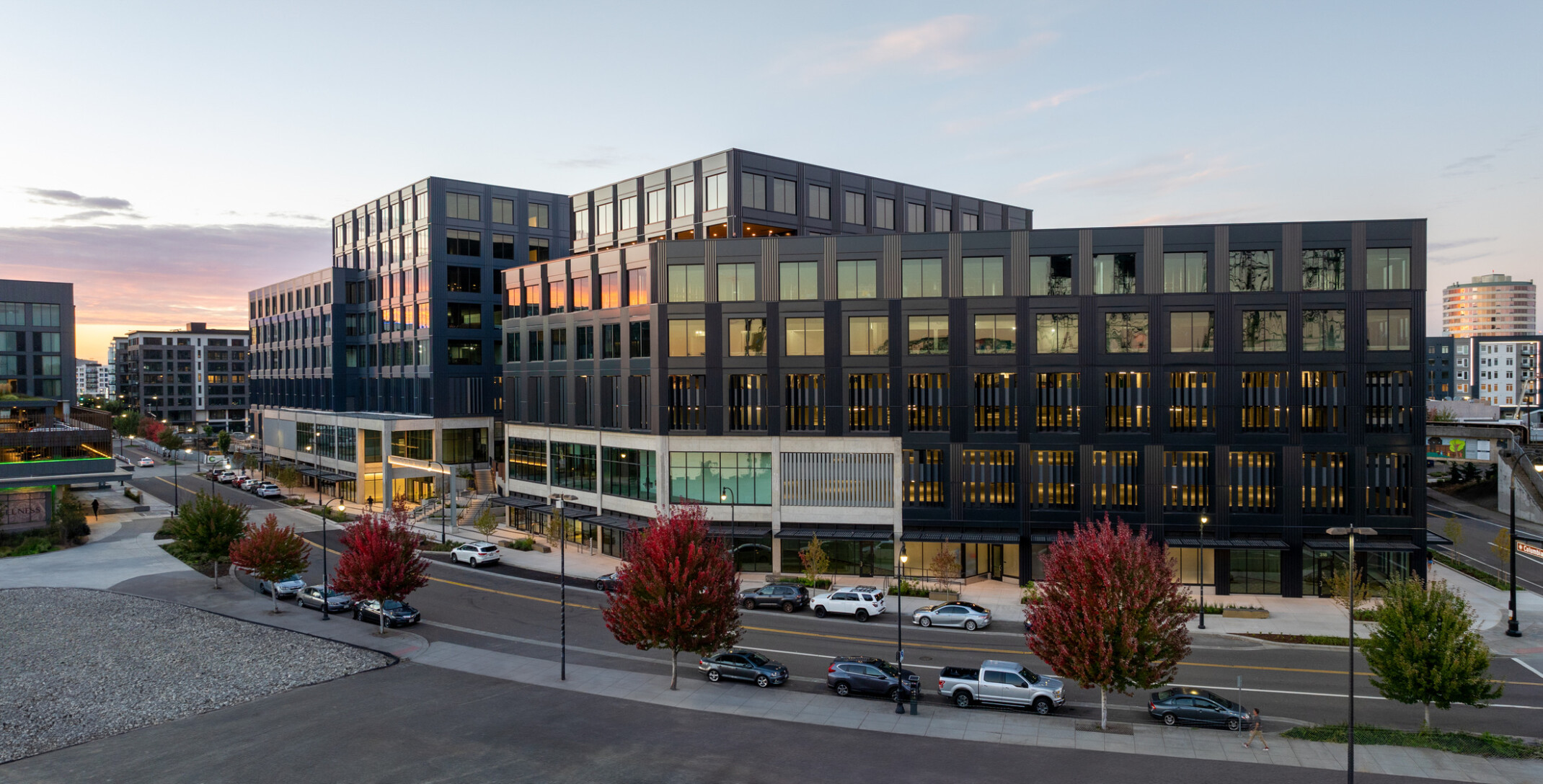 exterior view of mixed-use development in vancouver; dark grey facade highlighted by dusk sun