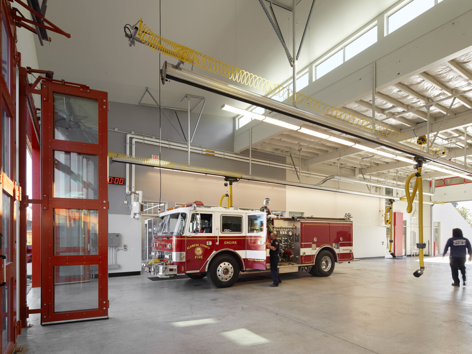 Fire station bay with red doors looking at a fire truck.