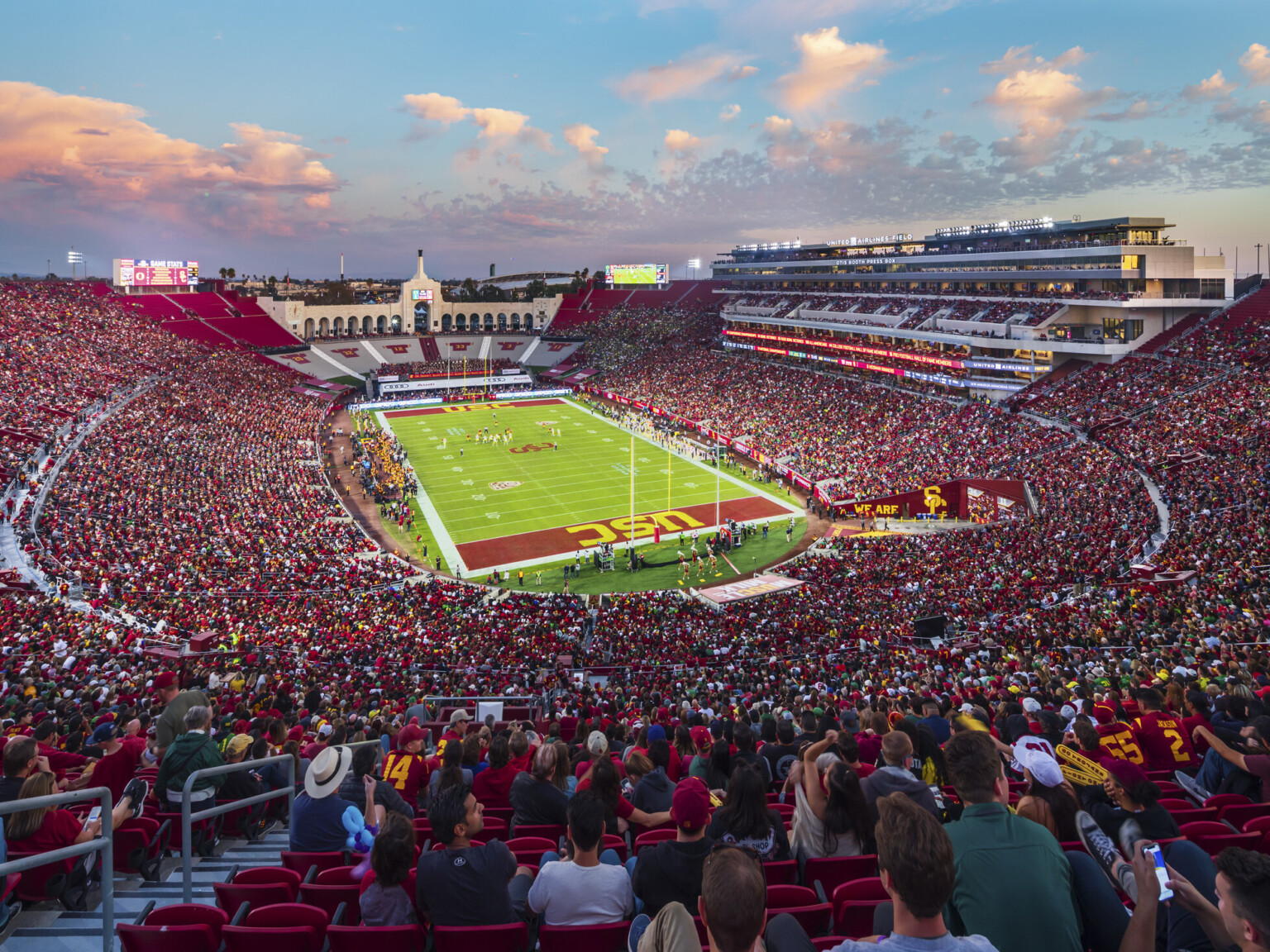 Full stadium of fans in red during dusk football game at the LA Memorial Coliseum