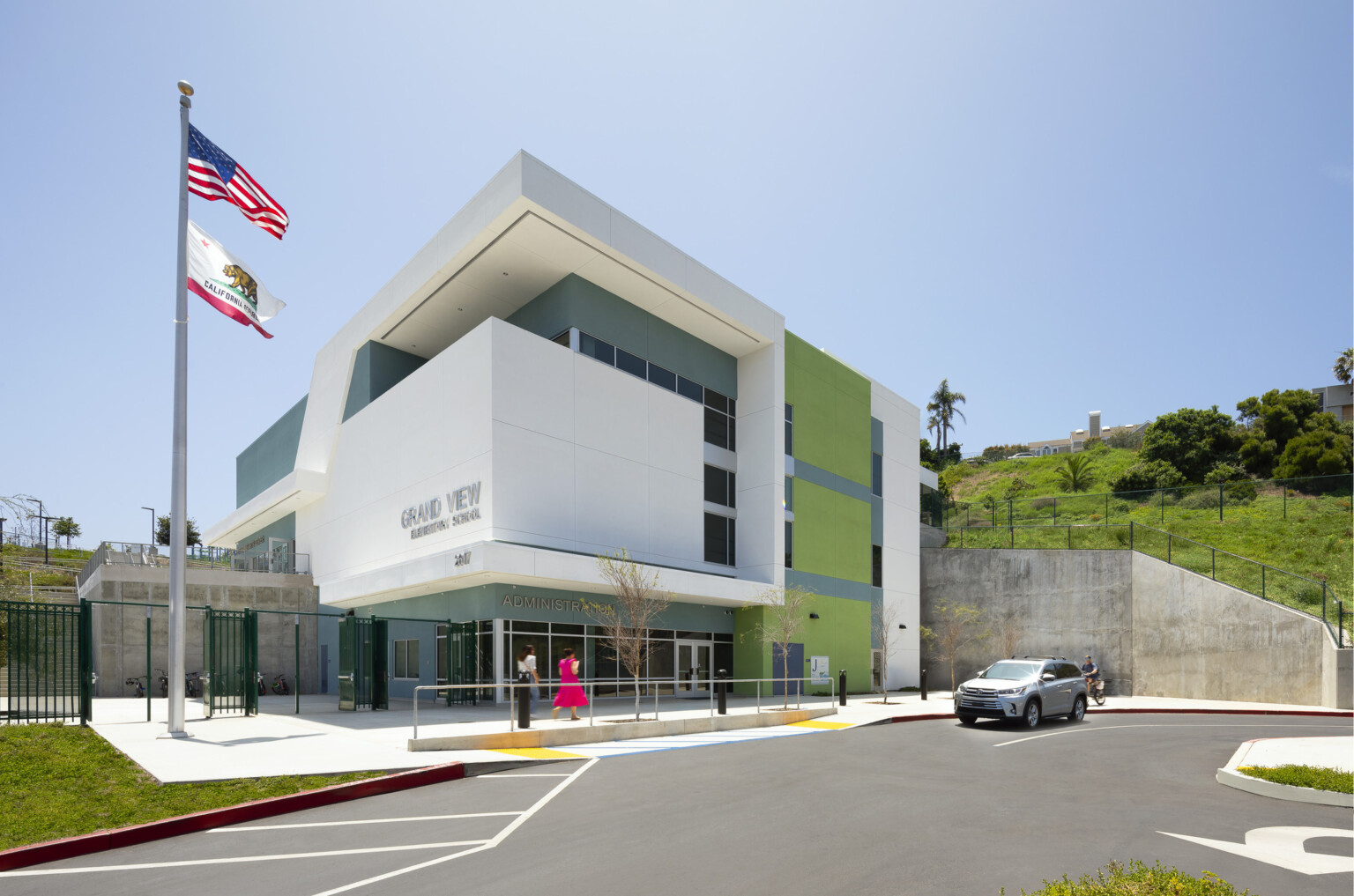 Rendering of a modern multistory building with green and blue accents, large hill with green grass in the back