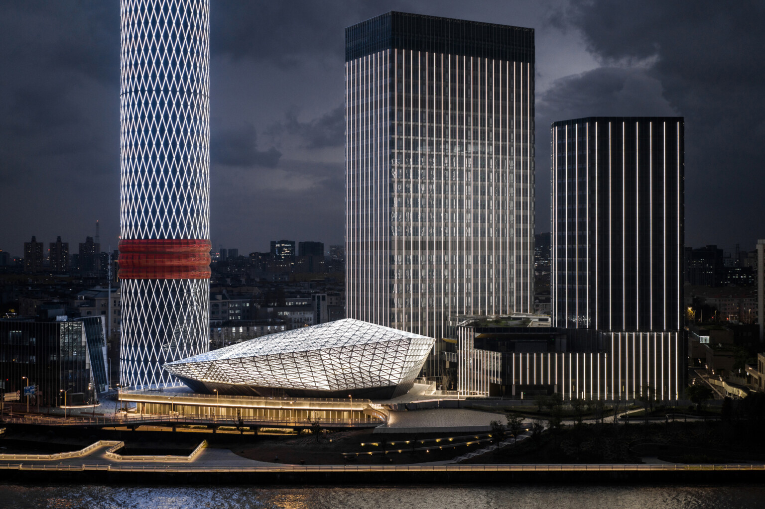 Baoshan Long Beach Complex illuminated at night along Shanghai's Yangtze River, diamond geometric light on cylindrical tower