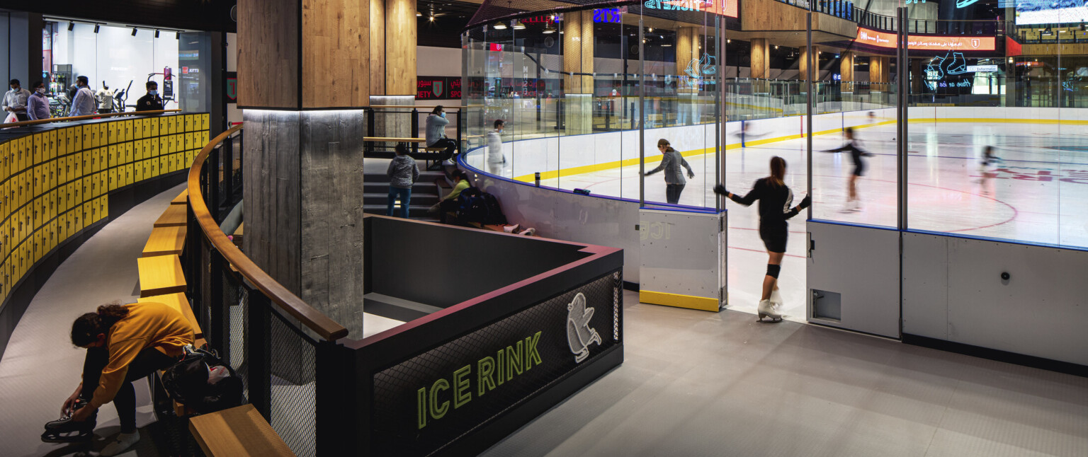 Ice rink showing the ice with an entry door surrounded by glass and yellow accents