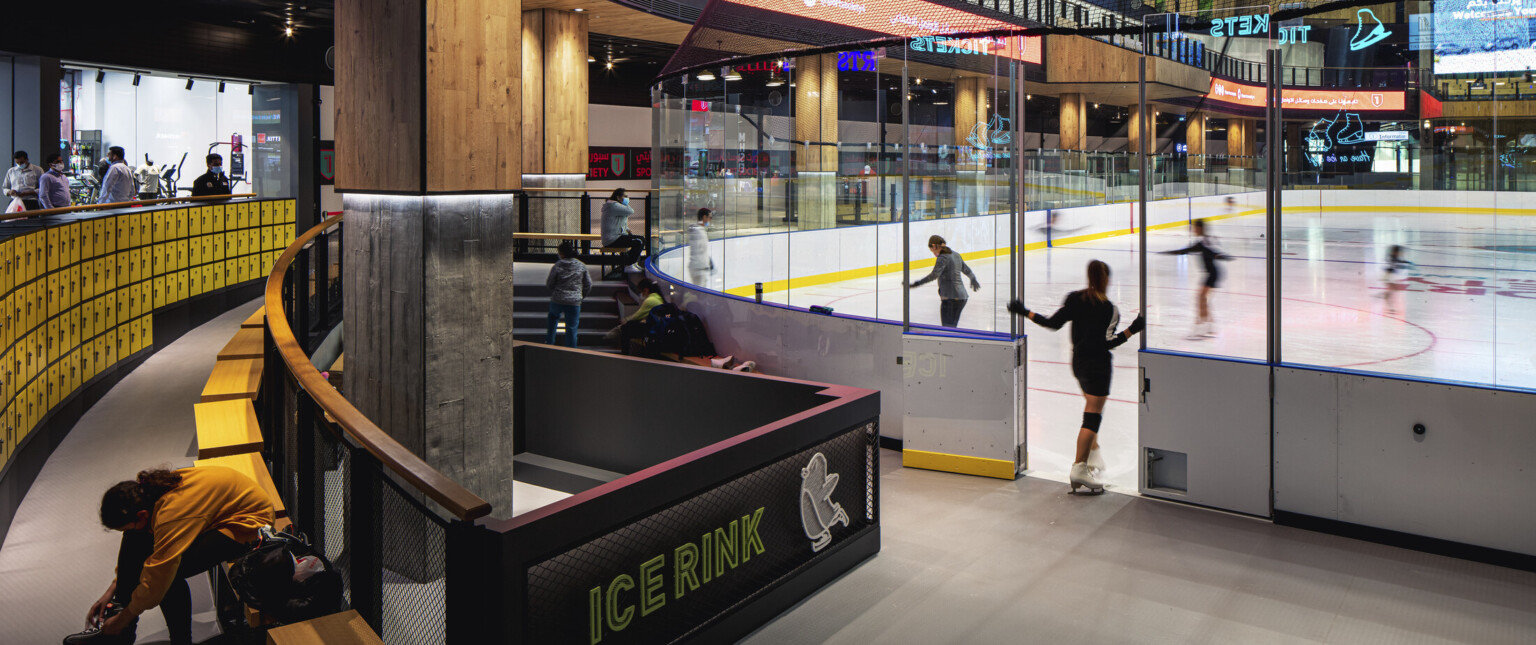 Ice rink showing the ice with an entry door surrounded by glass and yellow accents