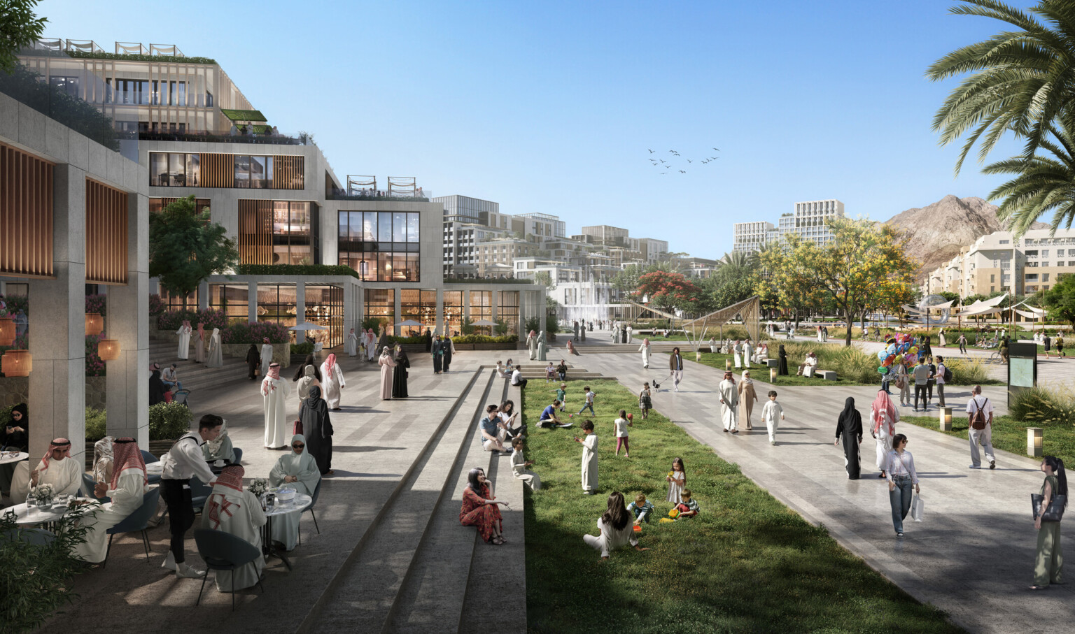 Daytime view of a lively public space featuring modern low-rise buildings, outdoor cafes, and well-maintained green areas. People are socializing, dining, and enjoying recreational activities, with palm trees and distant mountains enhancing the scenic backdrop.