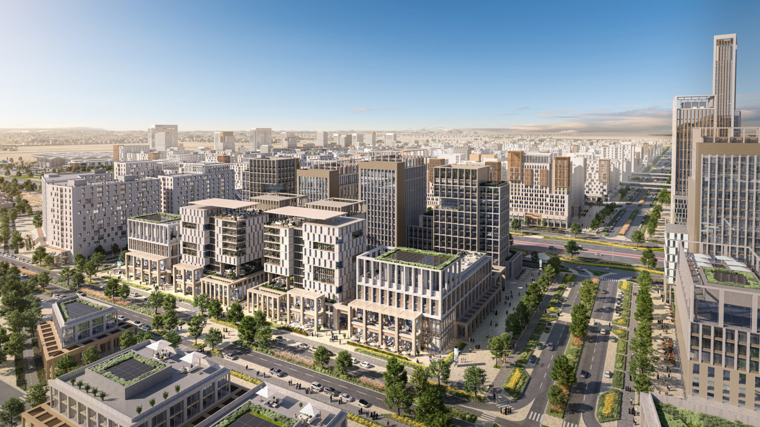 Aerial view of a modern urban development featuring mid-rise and high-rise buildings, green rooftops, wide roads, and ample green spaces, showcasing a well-planned cityscape.