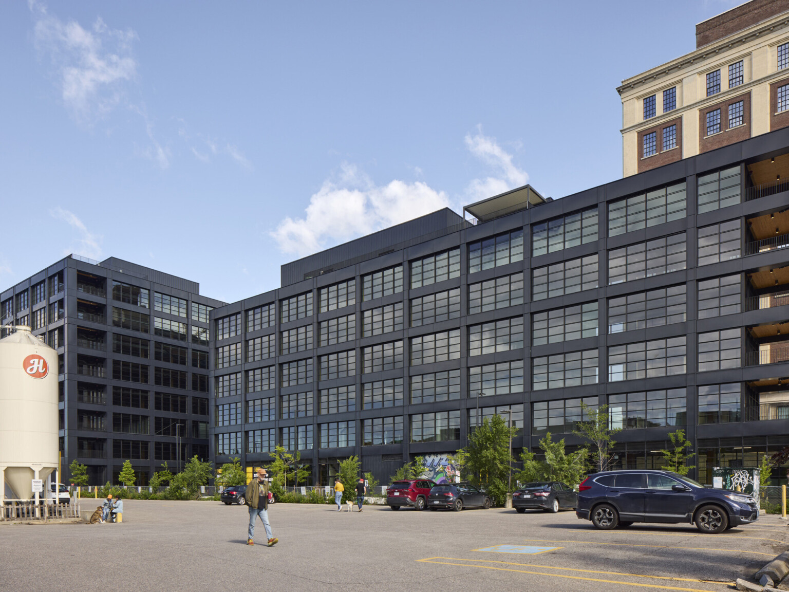 Black multistory office building filled with windows in front of a larger multistory office building