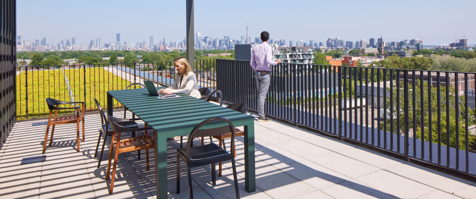 Outdoor seating area on a balcony overlooking a downtown skyline filled with large buildings.