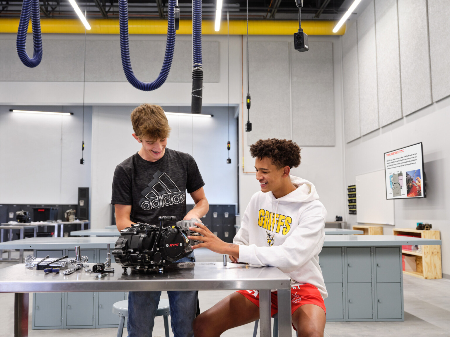 Two students working on mechanical equipment in a modern workshop classroom